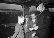 803546 Afbeelding van een conducteur van de N.S. in een trein tijdens het controleren van de vervoersbewijzen van een ...
